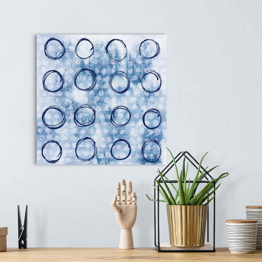 A bohemian room featuring Square abstract painting with indigo outlines of circles in rows in the foreground and smaller, s...