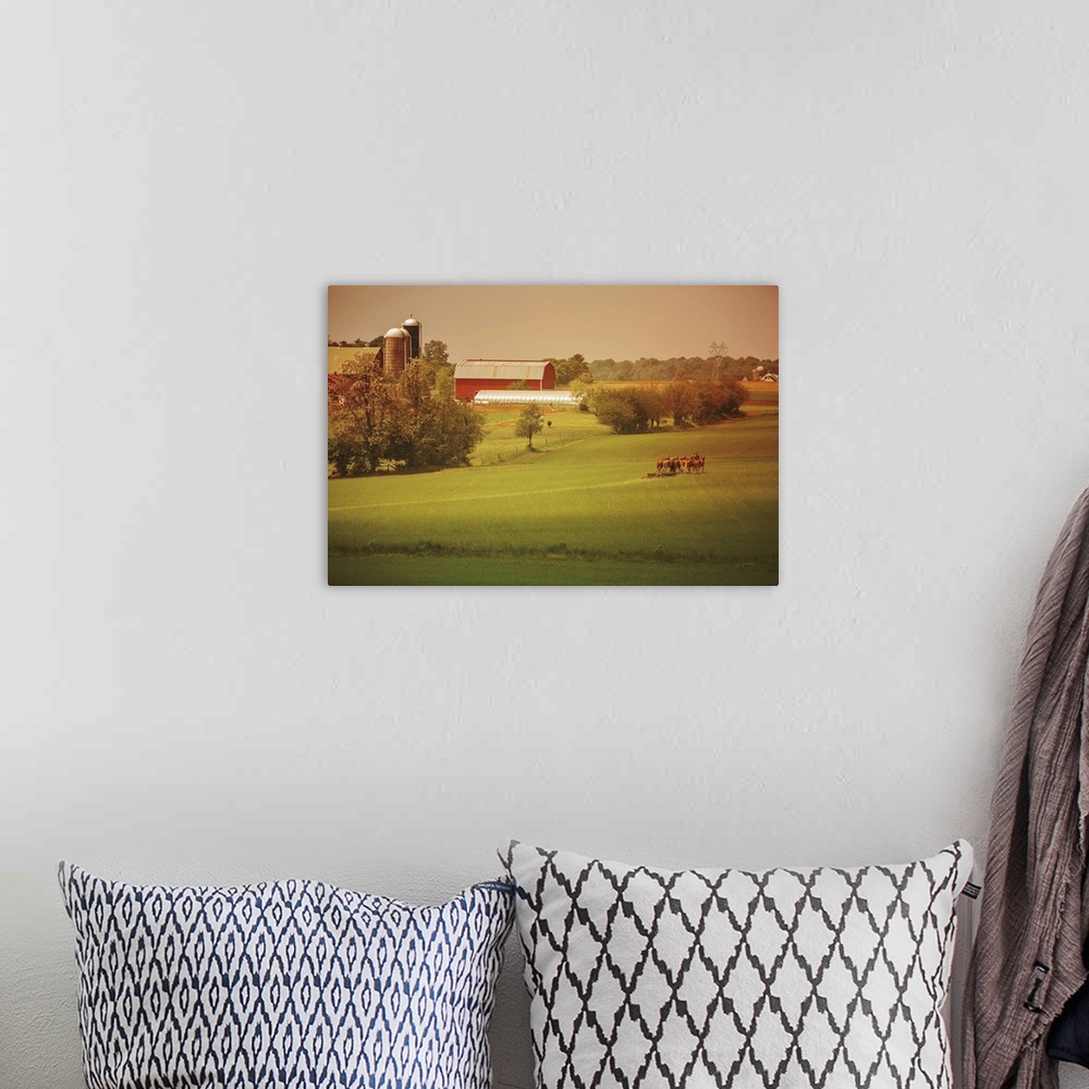 A bohemian room featuring Warm photograph of a farm scene, a tractor working in a field and a red barn in the background.