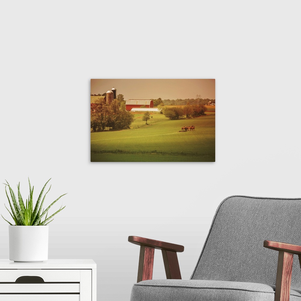 A modern room featuring Warm photograph of a farm scene, a tractor working in a field and a red barn in the background.