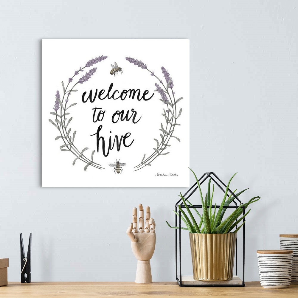 A bohemian room featuring "Welcome To Our Hive" framed with a wreath of purple flowers and bees.