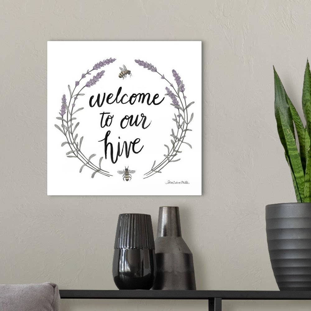 A modern room featuring "Welcome To Our Hive" framed with a wreath of purple flowers and bees.