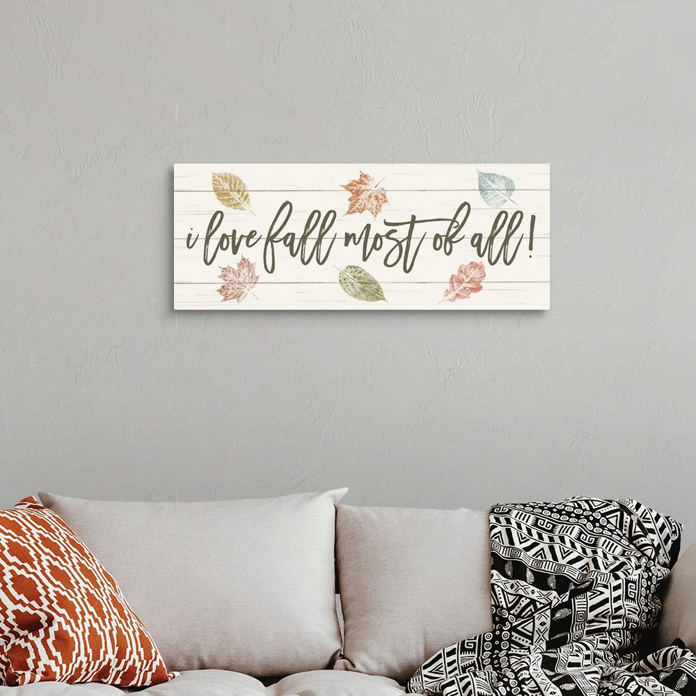 A bohemian room featuring "i love fall most of all!" on a white wood plank background with fall leaves.