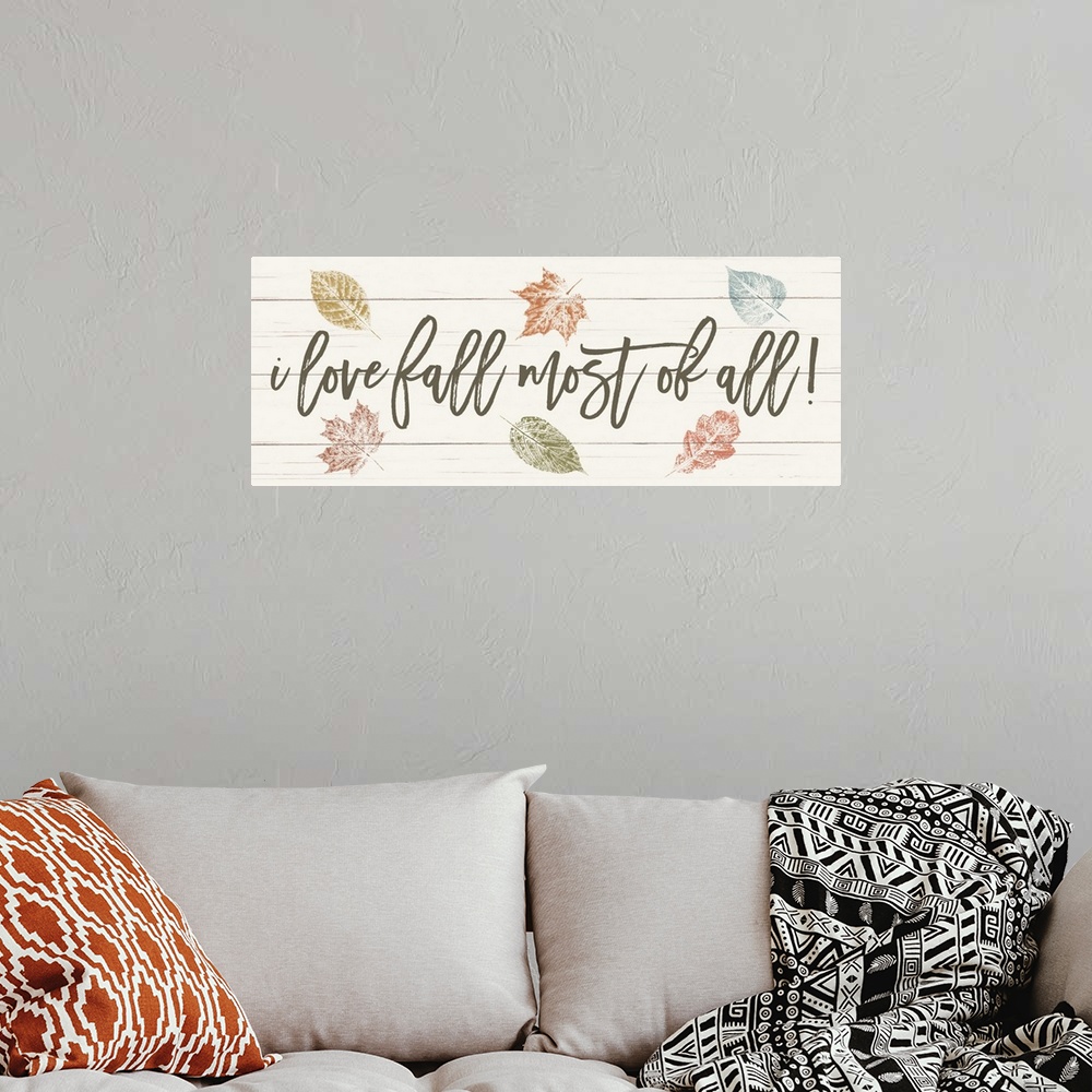 A bohemian room featuring "i love fall most of all!" on a white wood plank background with fall leaves.