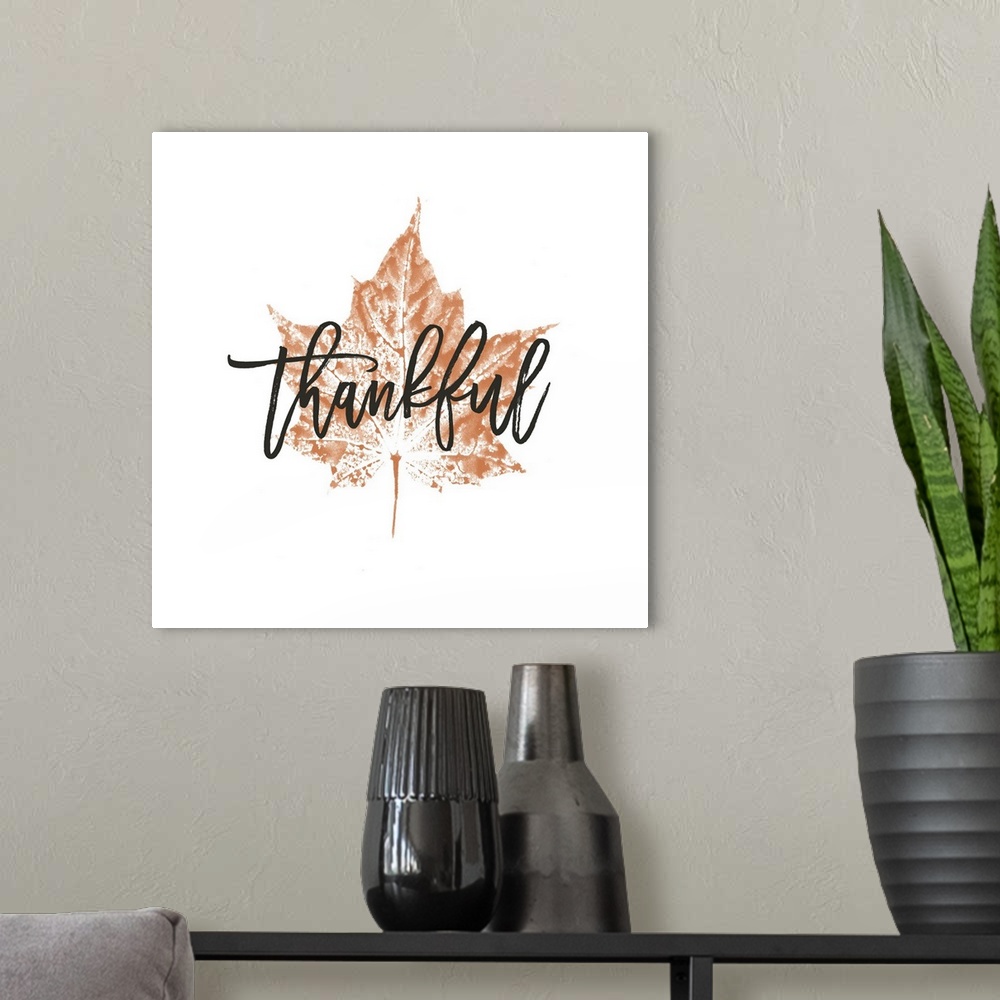 A modern room featuring "Thankful" over a metallic bronze leaf on white.