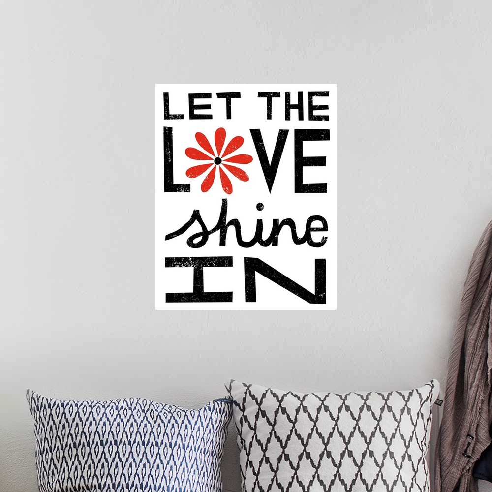 A bohemian room featuring "Let the love shine in" in bold black letters with a red flower.