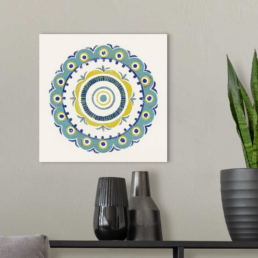 A modern room featuring Square decor with a mandala design in the center made in shades of blue, green, and yellow on a w...