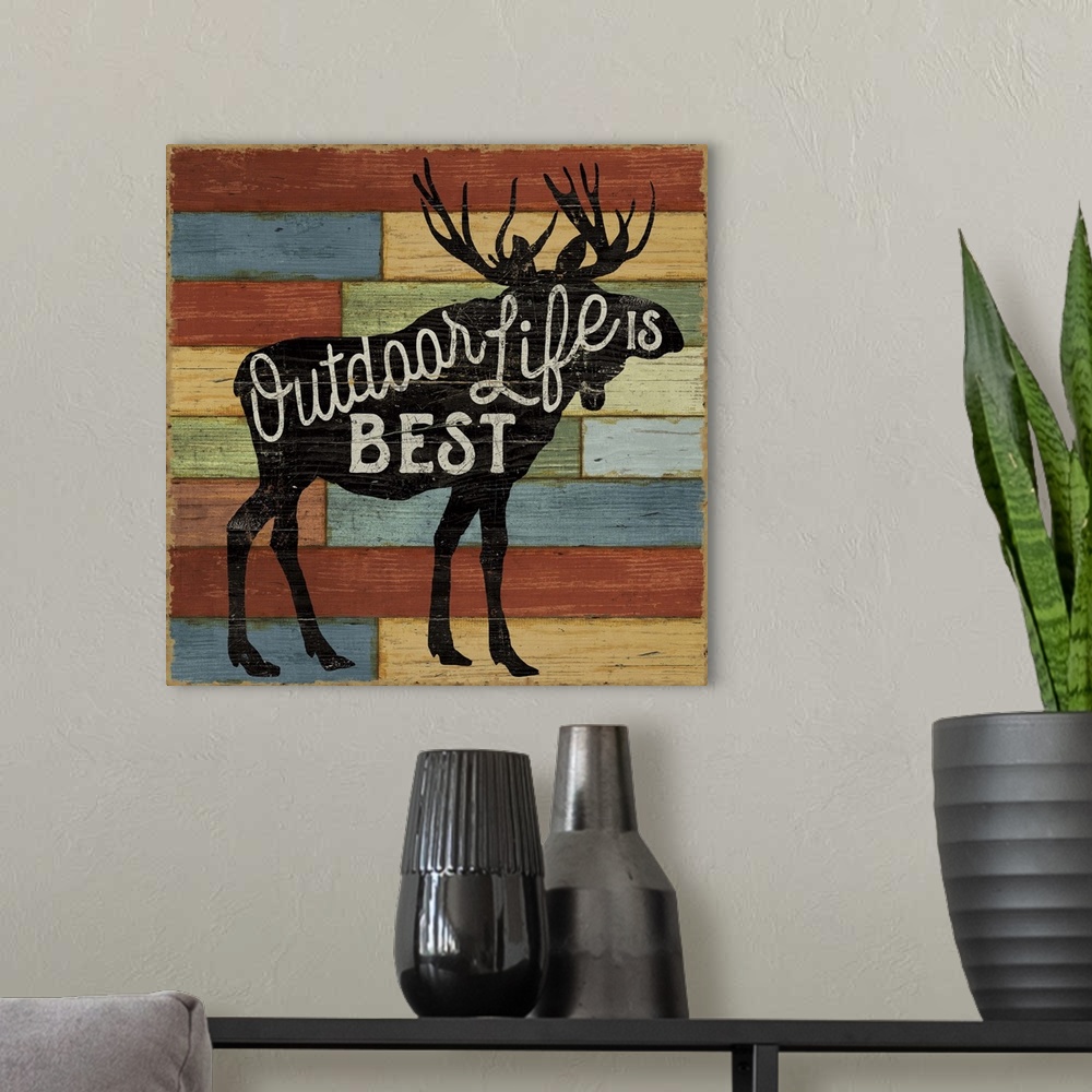 A modern room featuring Silhouette of a moose with white text over colorful wooden boards.