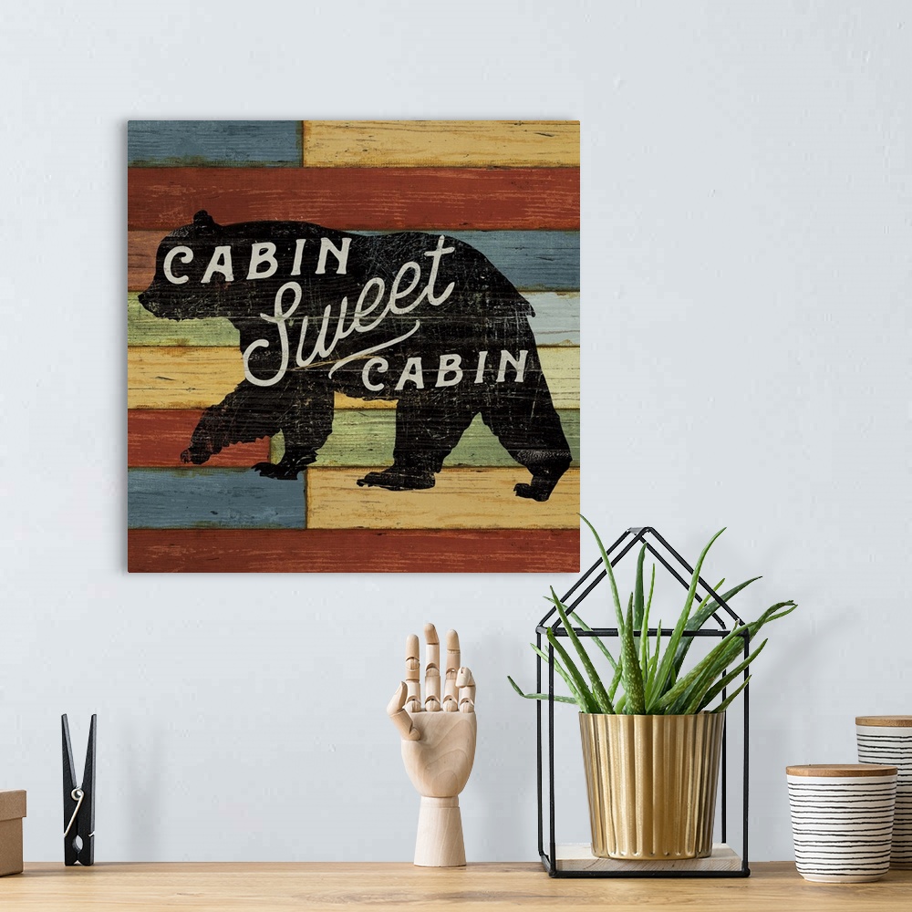 A bohemian room featuring Silhouette of a bear with white text over colorful wooden boards.