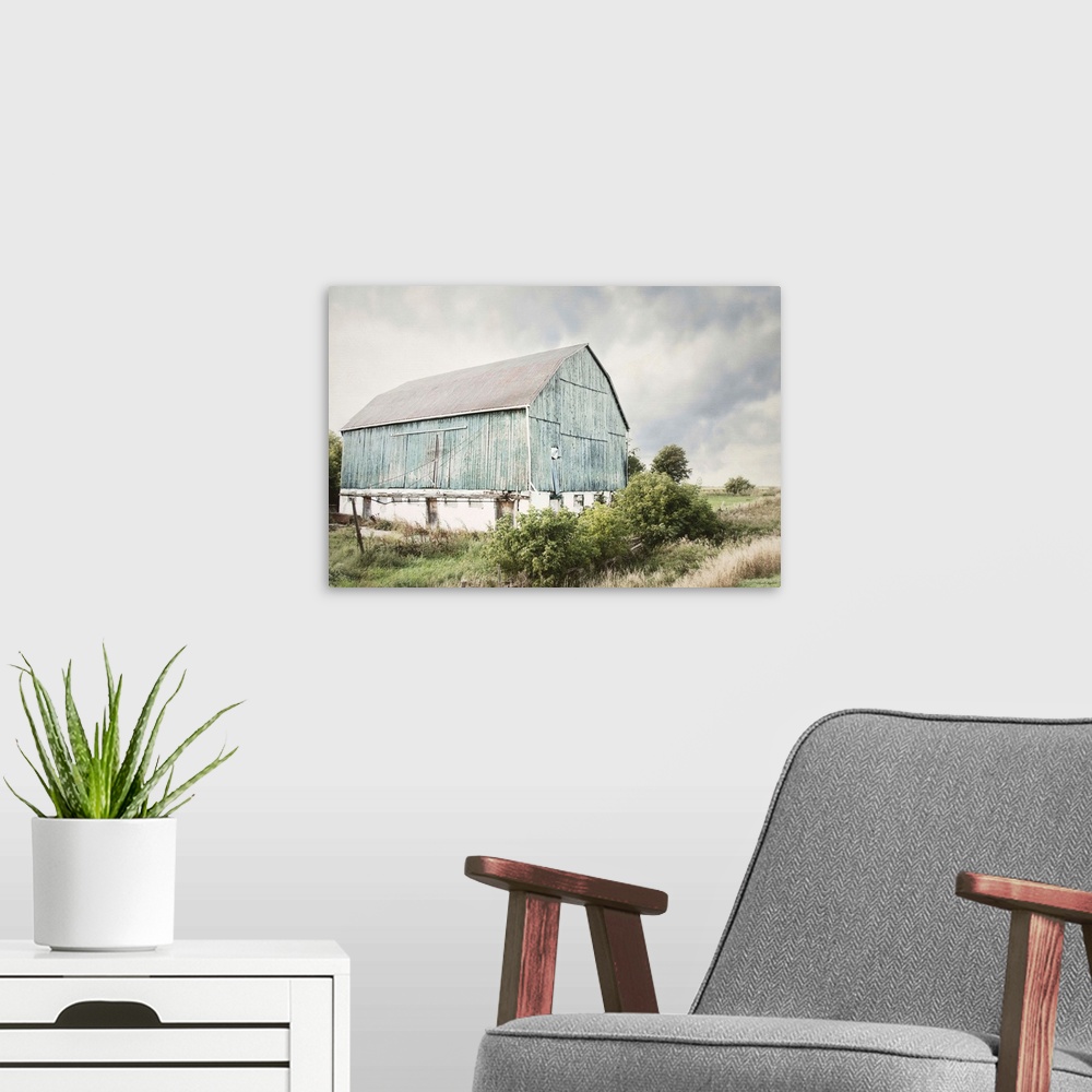A modern room featuring Photograph of an old faded light blue barn in an overgrown rural field.