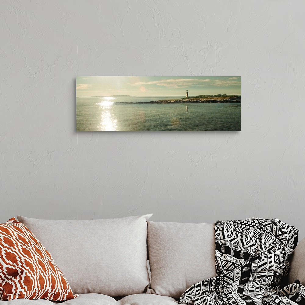 A bohemian room featuring Panoramic photograph of a lighthouse on the sound with the sun shining on the water.