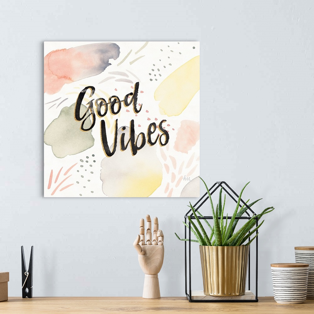 A bohemian room featuring "Good Vibes" written in black and gold on a  decorative watercolor background.