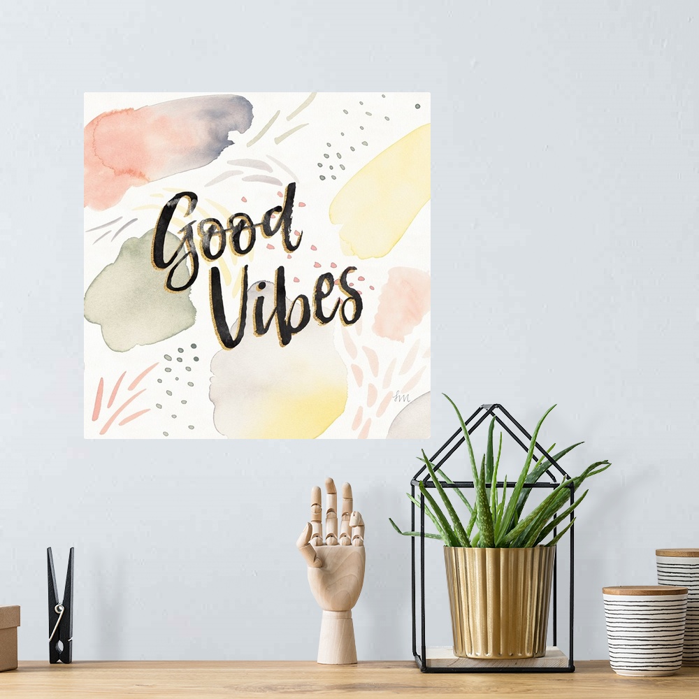 A bohemian room featuring "Good Vibes" written in black and gold on a  decorative watercolor background.