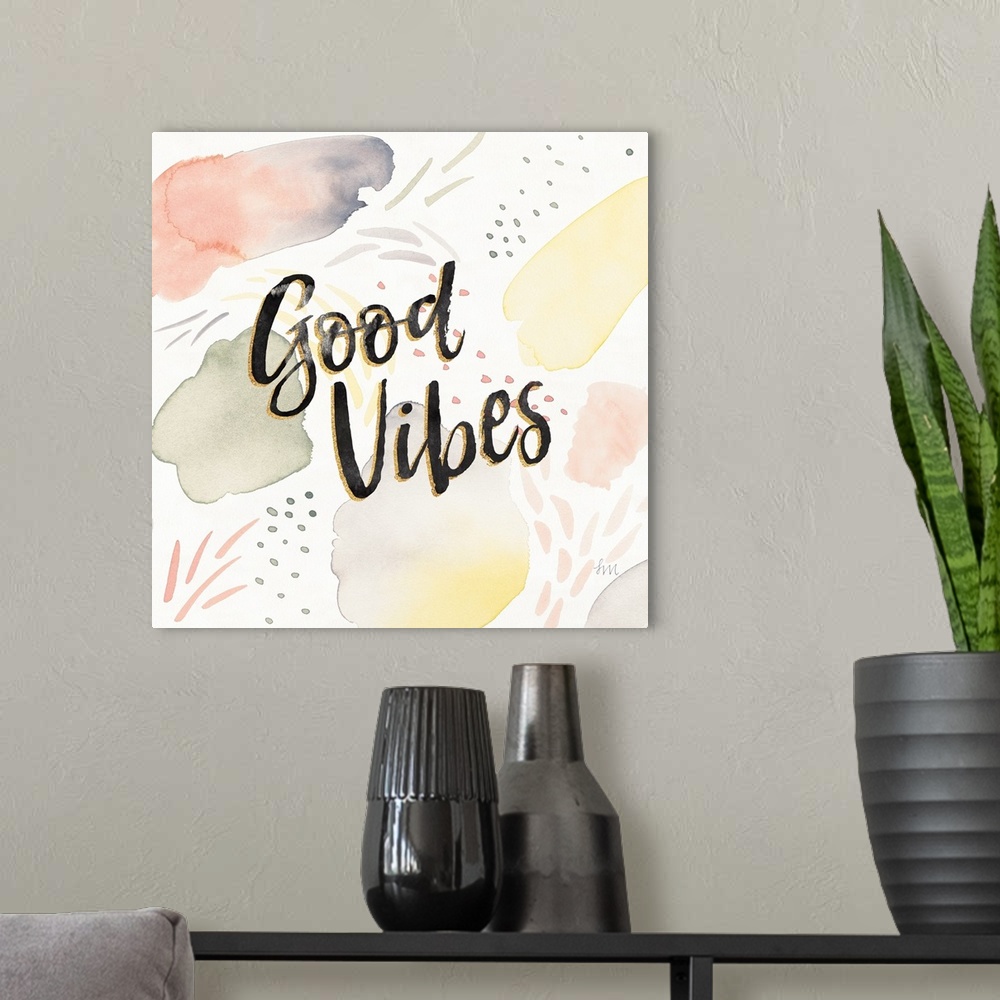 A modern room featuring "Good Vibes" written in black and gold on a  decorative watercolor background.