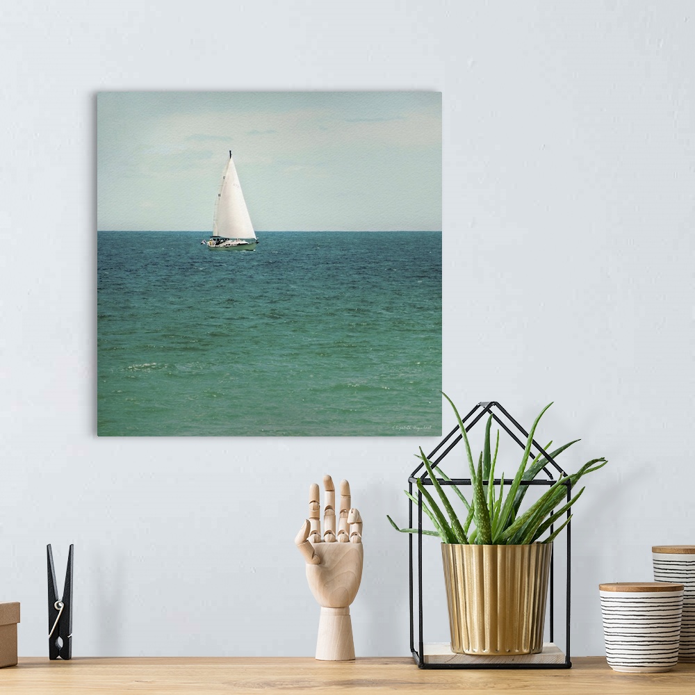 A bohemian room featuring A photograph of a sailboat out on a green sea.