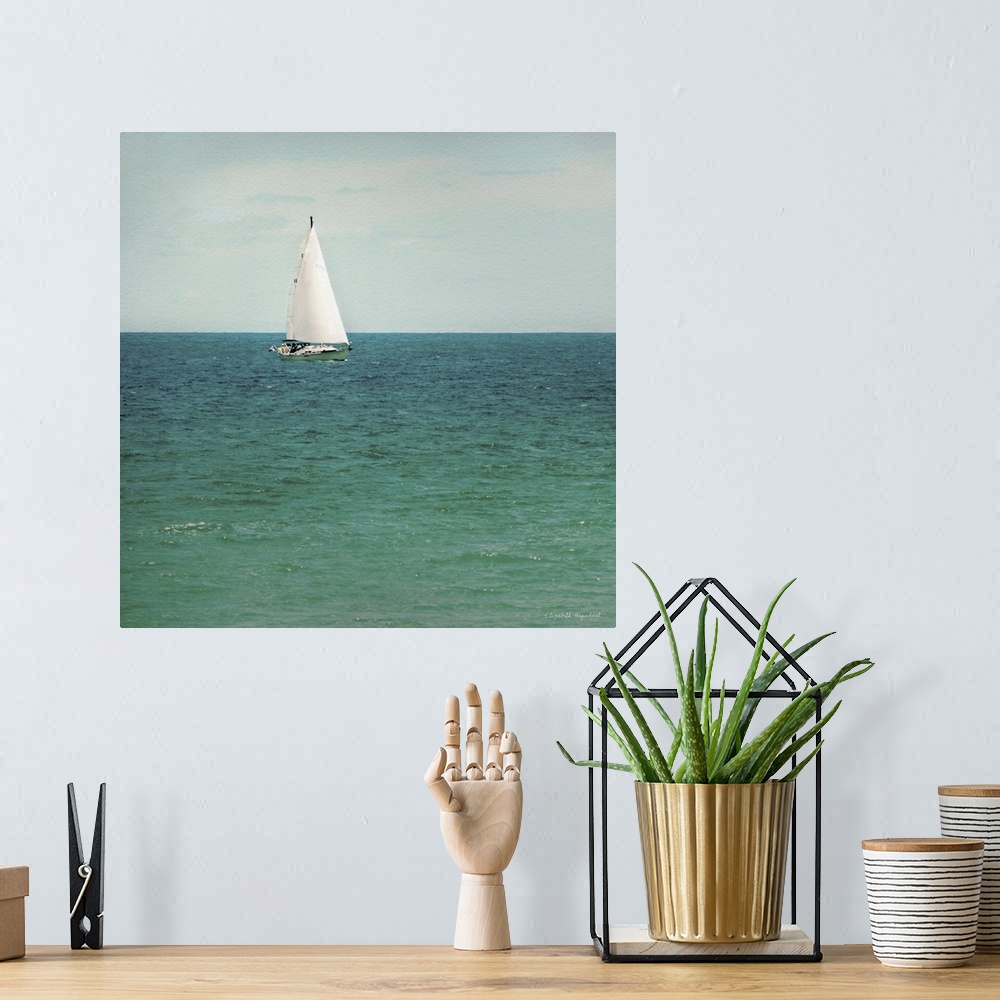 A bohemian room featuring A photograph of a sailboat out on a green sea.