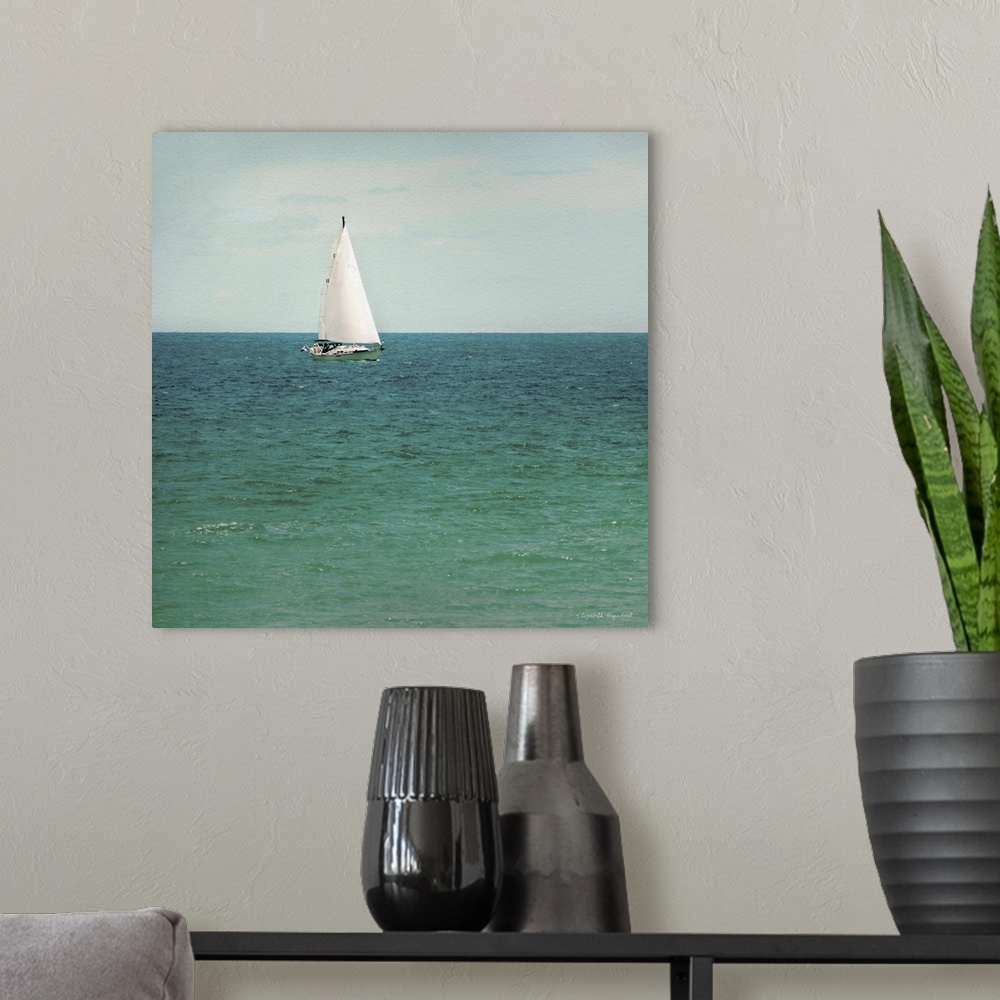 A modern room featuring A photograph of a sailboat out on a green sea.