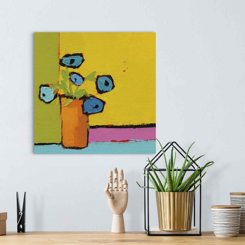 A bohemian room featuring Bright square abstract painting of an orange vase with bright blue flowers on a multicolored back...