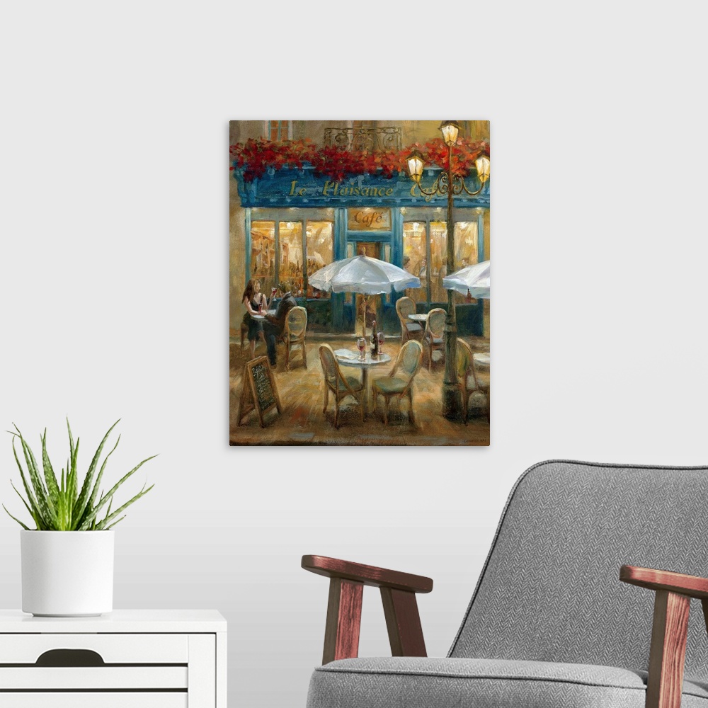A modern room featuring Painting of tables and chairs outside of a street cafo at night with flowerbox over front door en...