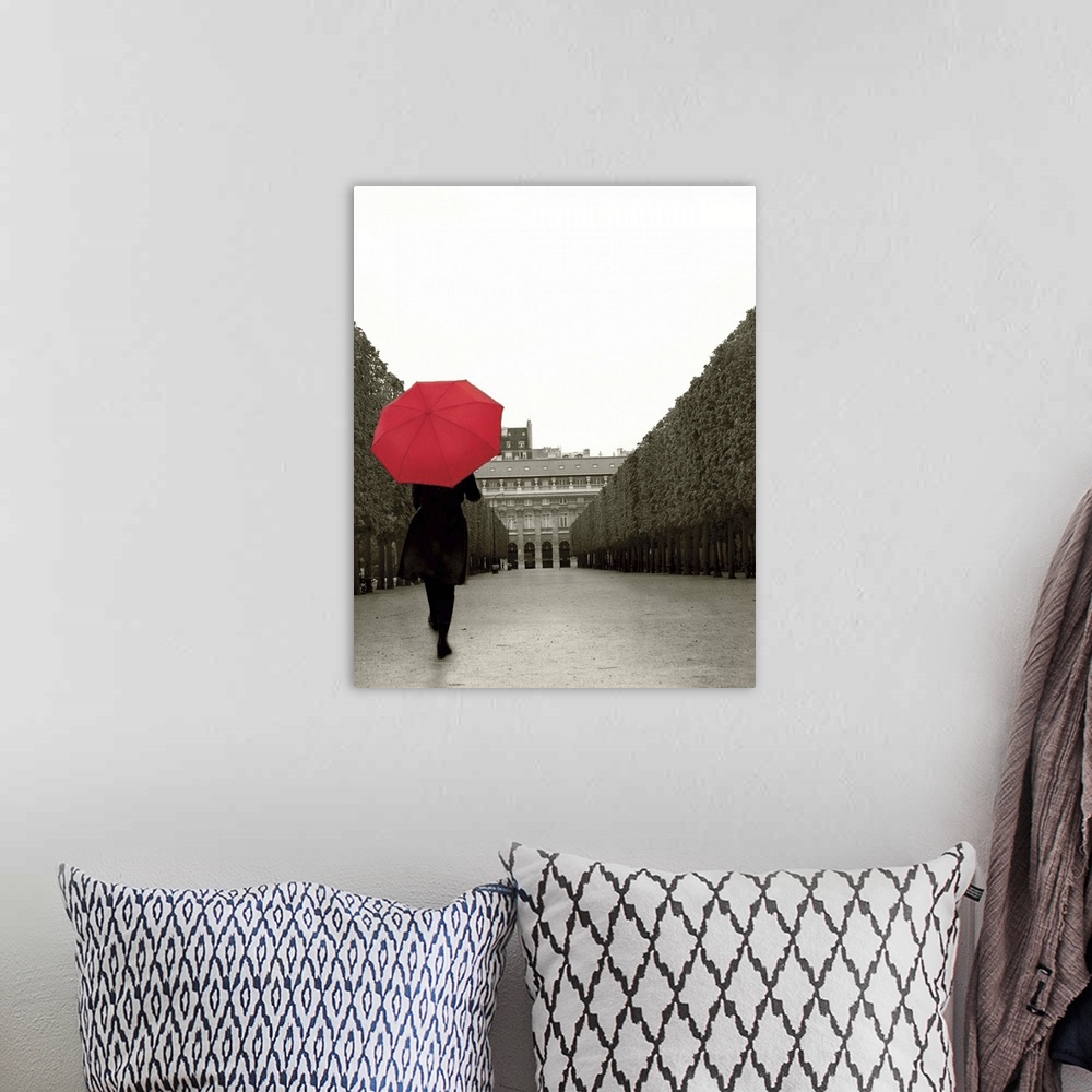 A bohemian room featuring A photograph of a person walking down an empty road with a red umbrella overhead.