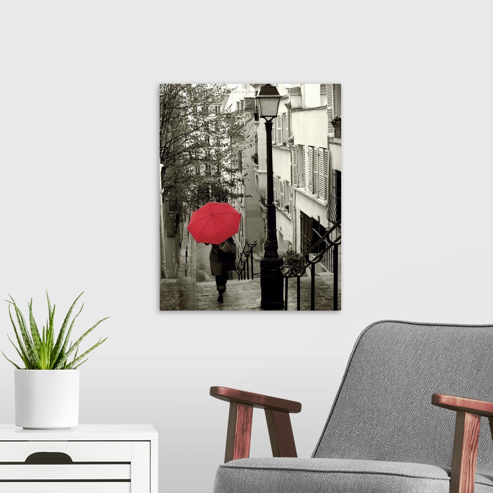 A modern room featuring A photograph of a person walking down an empty neighborhood corridor with a red umbrella overhead.