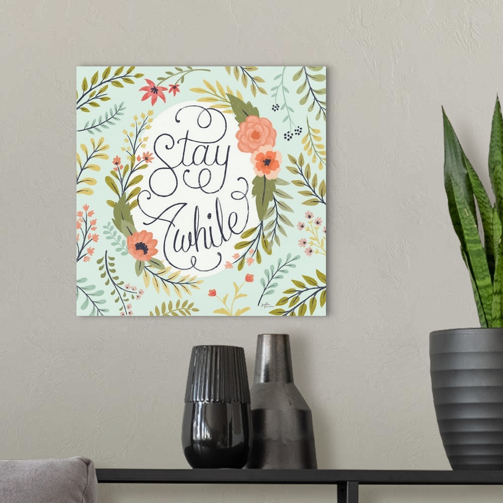 A modern room featuring "Stay Awhile" handwritten with loopy finishes, inside of a floral display on a mint colored backg...