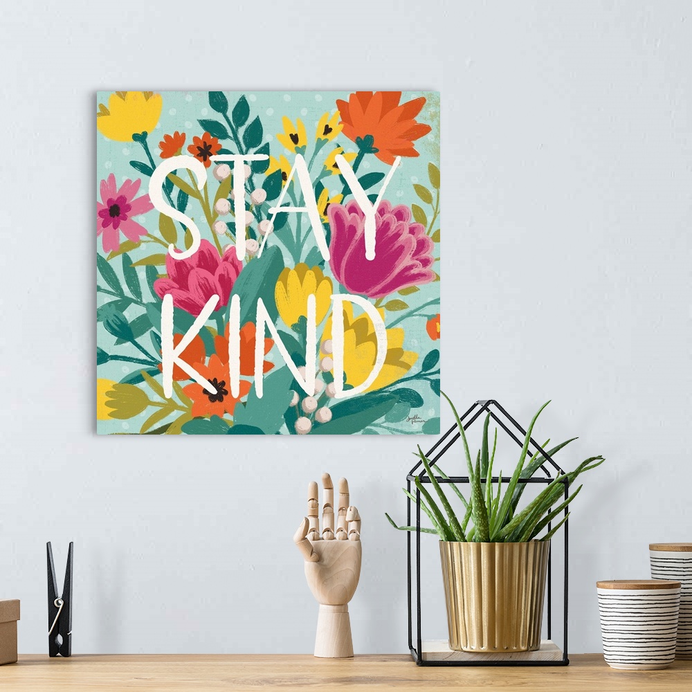 A bohemian room featuring This decorative artwork features the words, 'Stay Kind' over a blue polka dot background with spr...