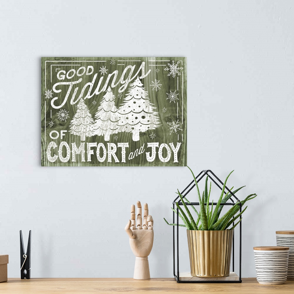 A bohemian room featuring "Good Tidings of Comfort and Joy" decorative holiday art on a green wood background.