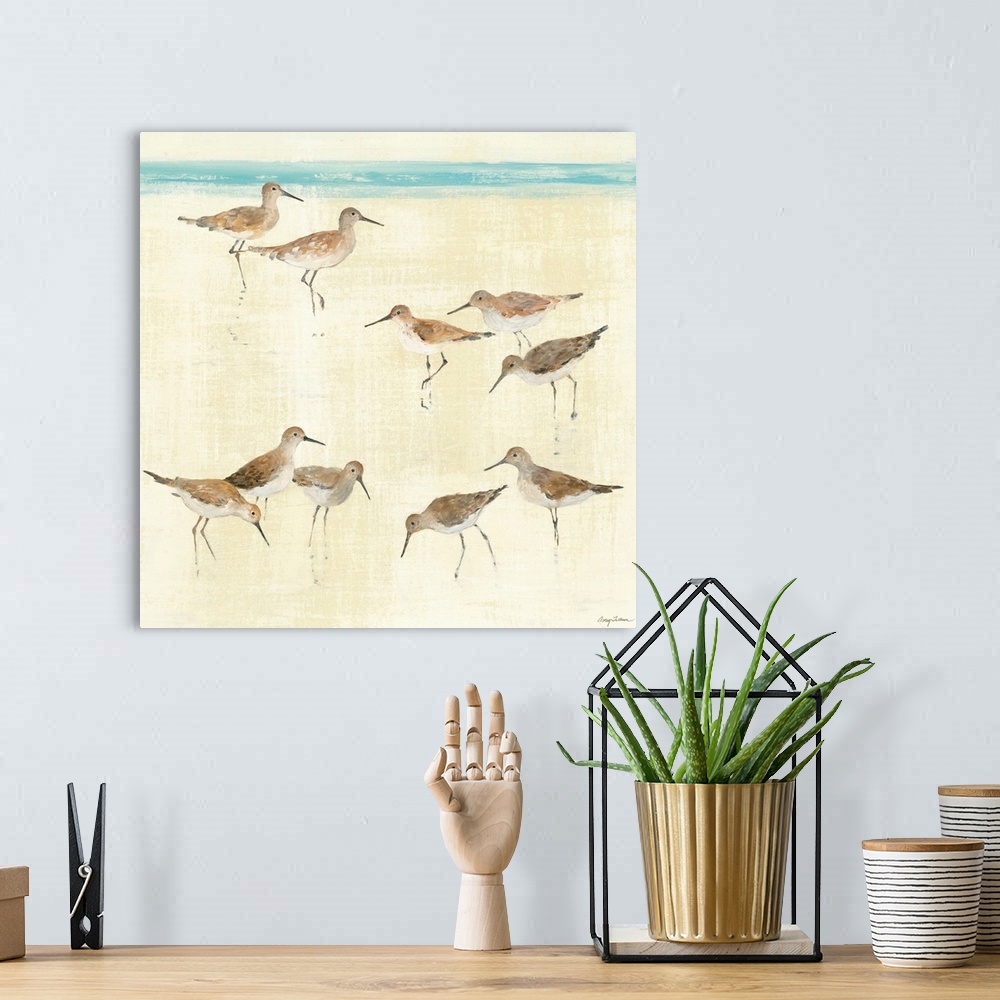 A bohemian room featuring Square, large artwork of a group of sandpiper birds standing on the beach, near the edge of blue ...
