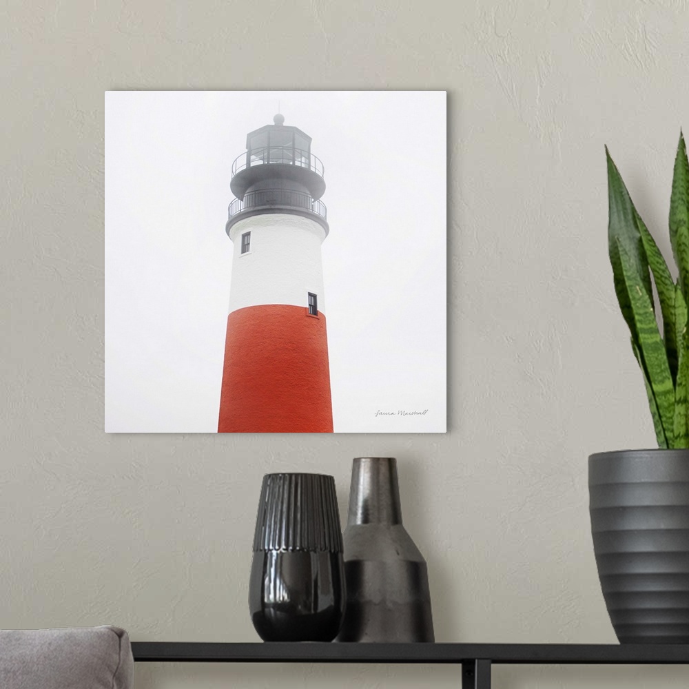 A modern room featuring A square photograph of the Sankaty Head Lighthouse in Nantucket Island, Massachusetts, blanketed ...
