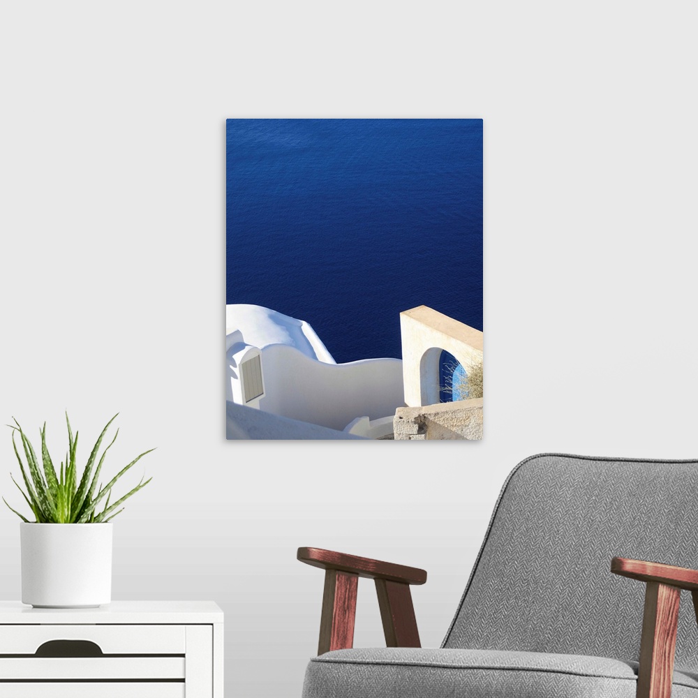 A modern room featuring Landscape photograph of the bright blue water in Santorini.