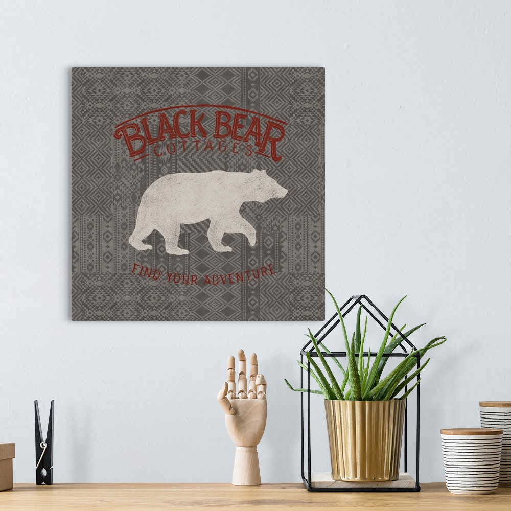 A bohemian room featuring "Black Bear Cottages" "Find Your Adventure" written in red on a gray patterned background with a ...