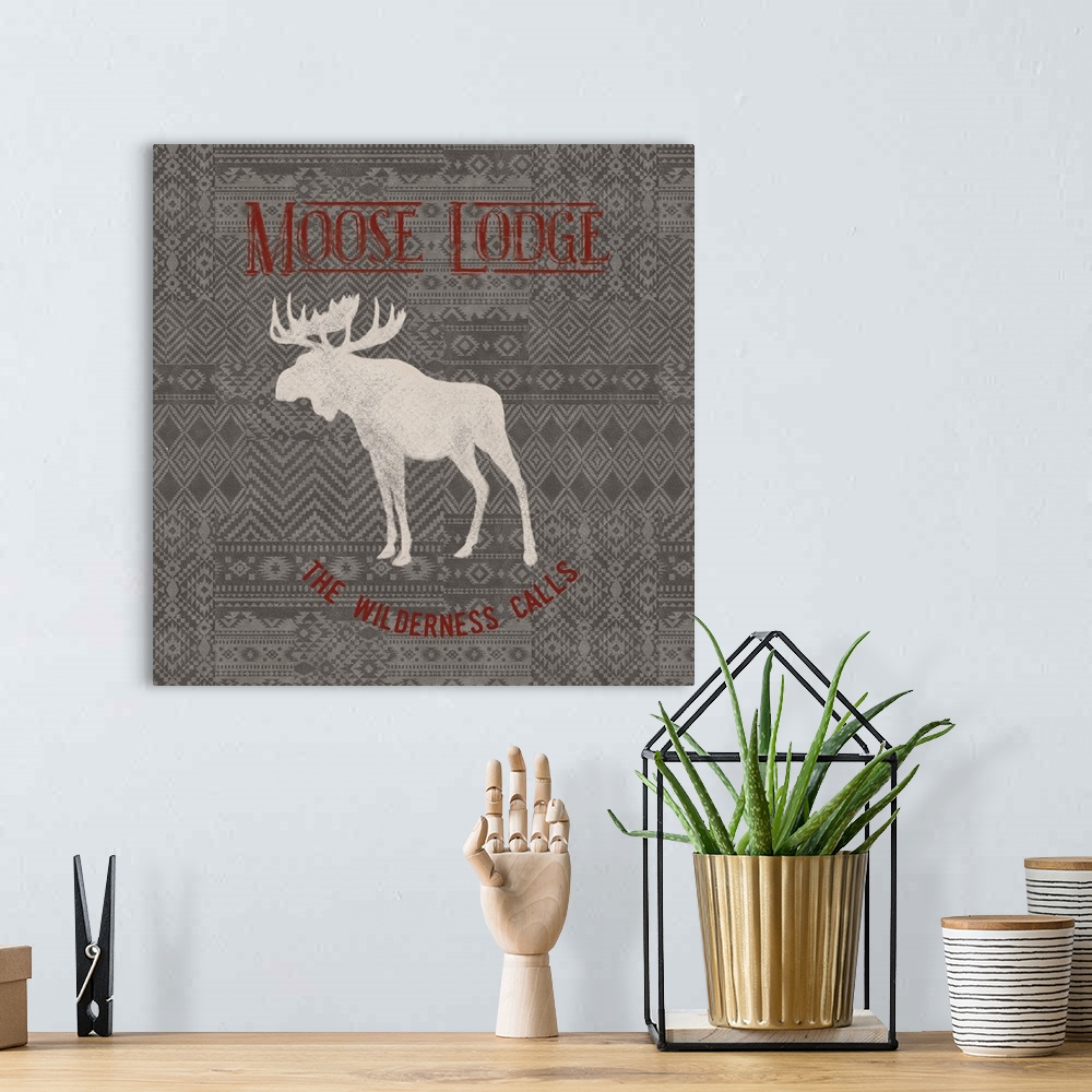 A bohemian room featuring "Moose Lodge" "The Wilderness Calls" written in red on a gray patterned background with a white s...