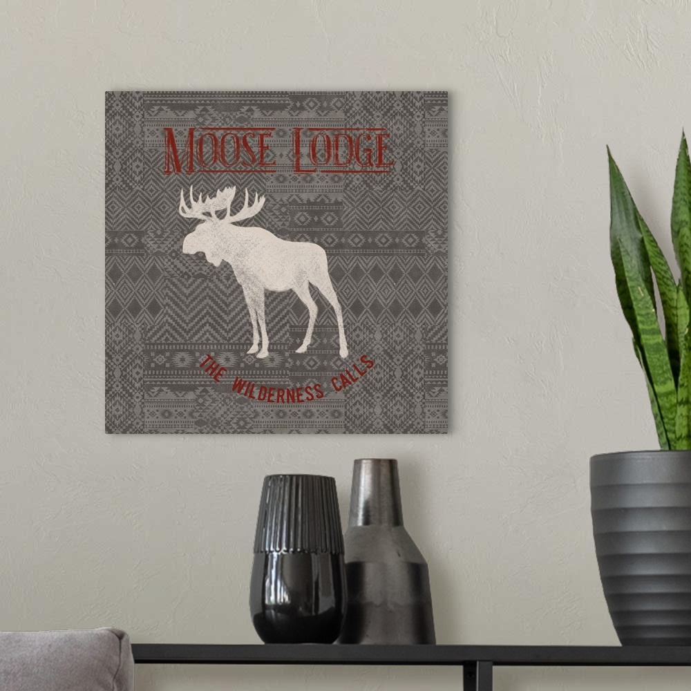 A modern room featuring "Moose Lodge" "The Wilderness Calls" written in red on a gray patterned background with a white s...