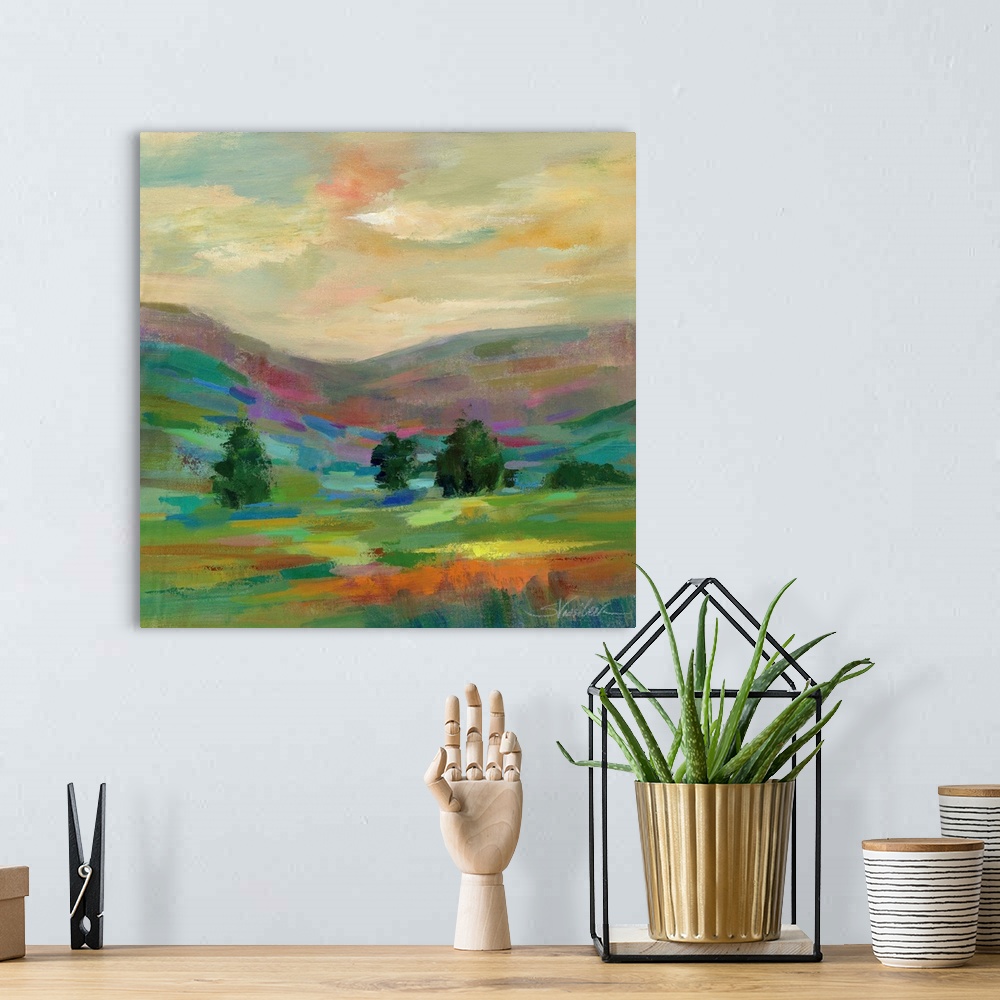A bohemian room featuring Contemporary artwork of a hilly landscape with a few trees.
