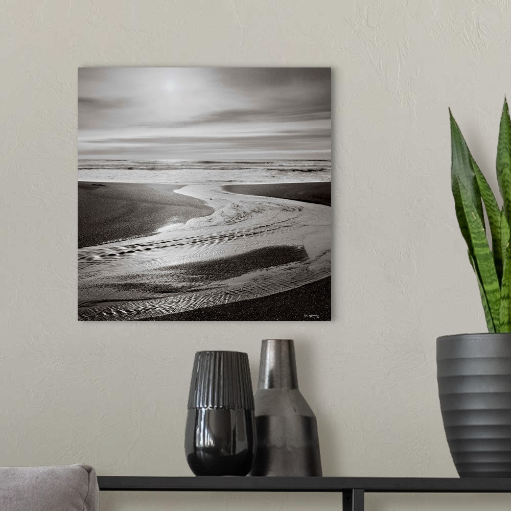 A modern room featuring Black and white photograph of a beach with the sun setting in the background.