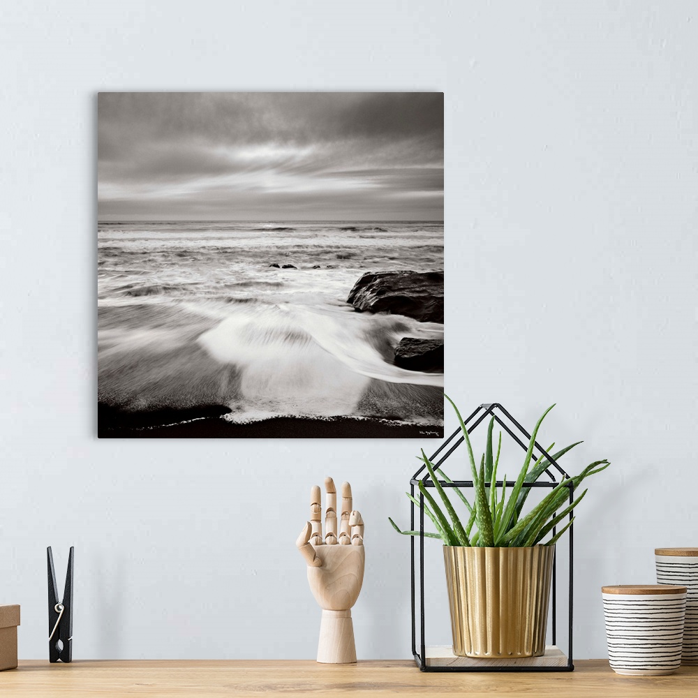 A bohemian room featuring Black and white photograph of a seascape with the ocean waves hitting the rocky shoreline.