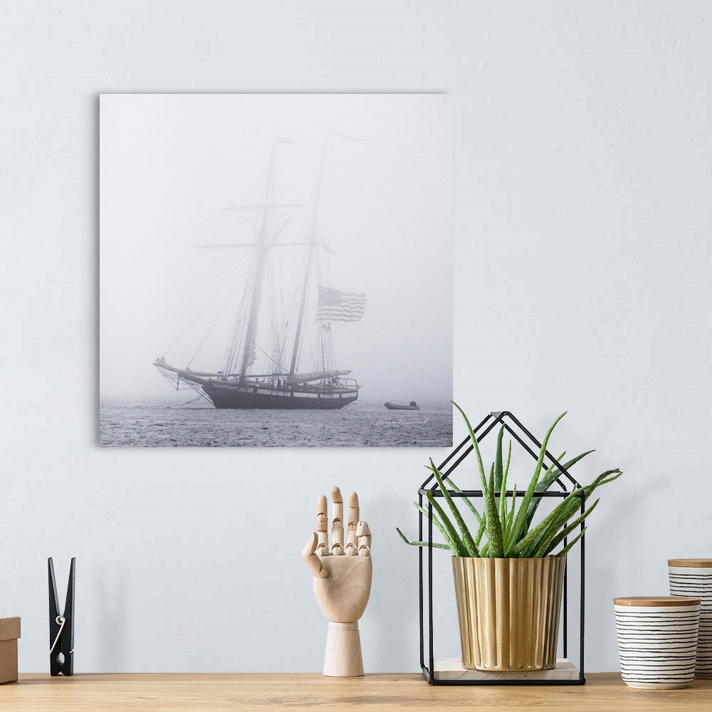 A bohemian room featuring A square photograph of a large sail boat blanketed in a heavy fog.
