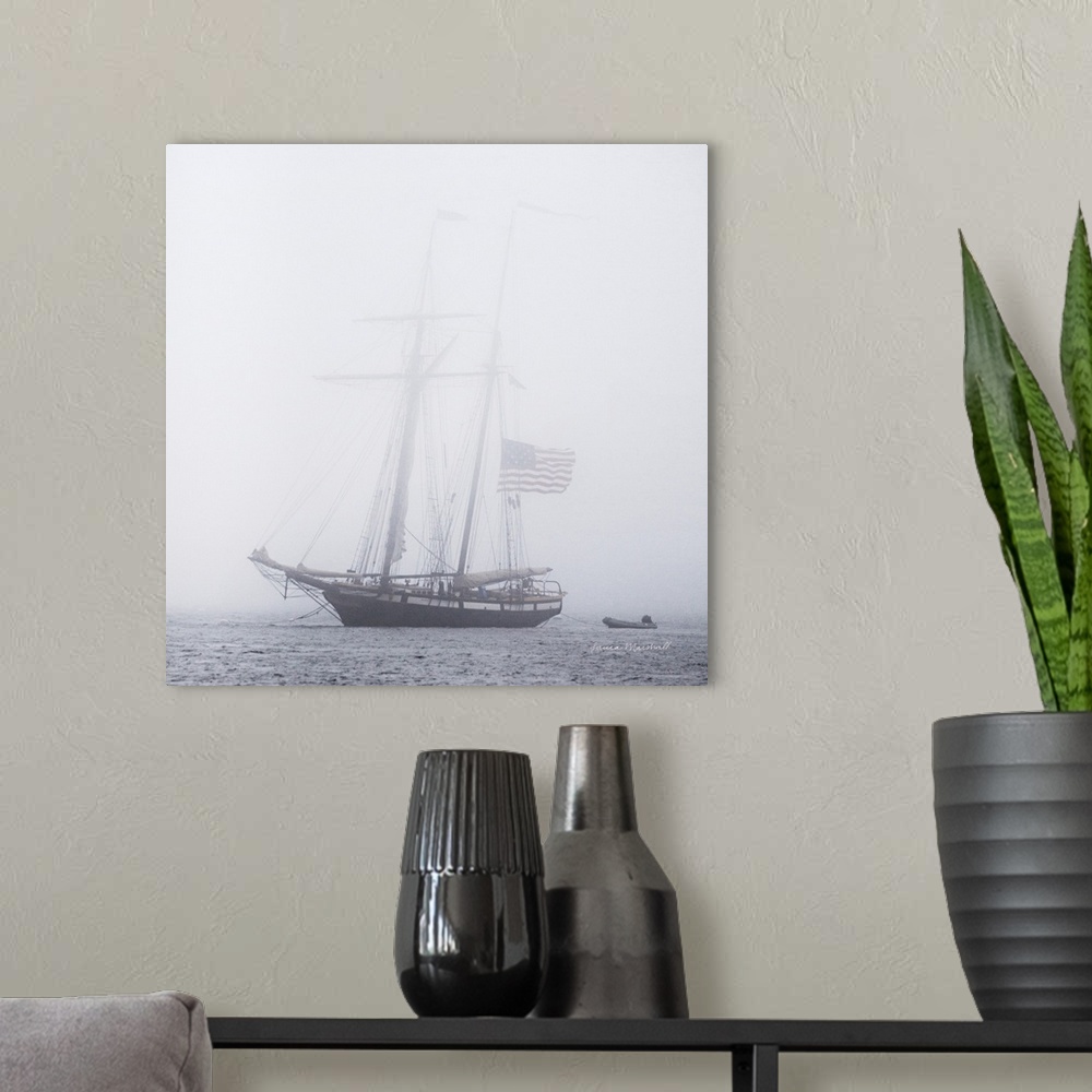 A modern room featuring A square photograph of a large sail boat blanketed in a heavy fog.