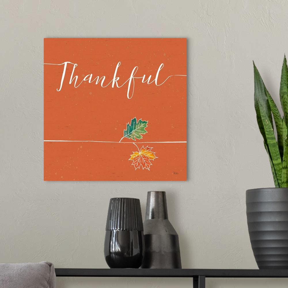 A modern room featuring "Thankful" with a pair of fall leaves on a wood textured orange background.