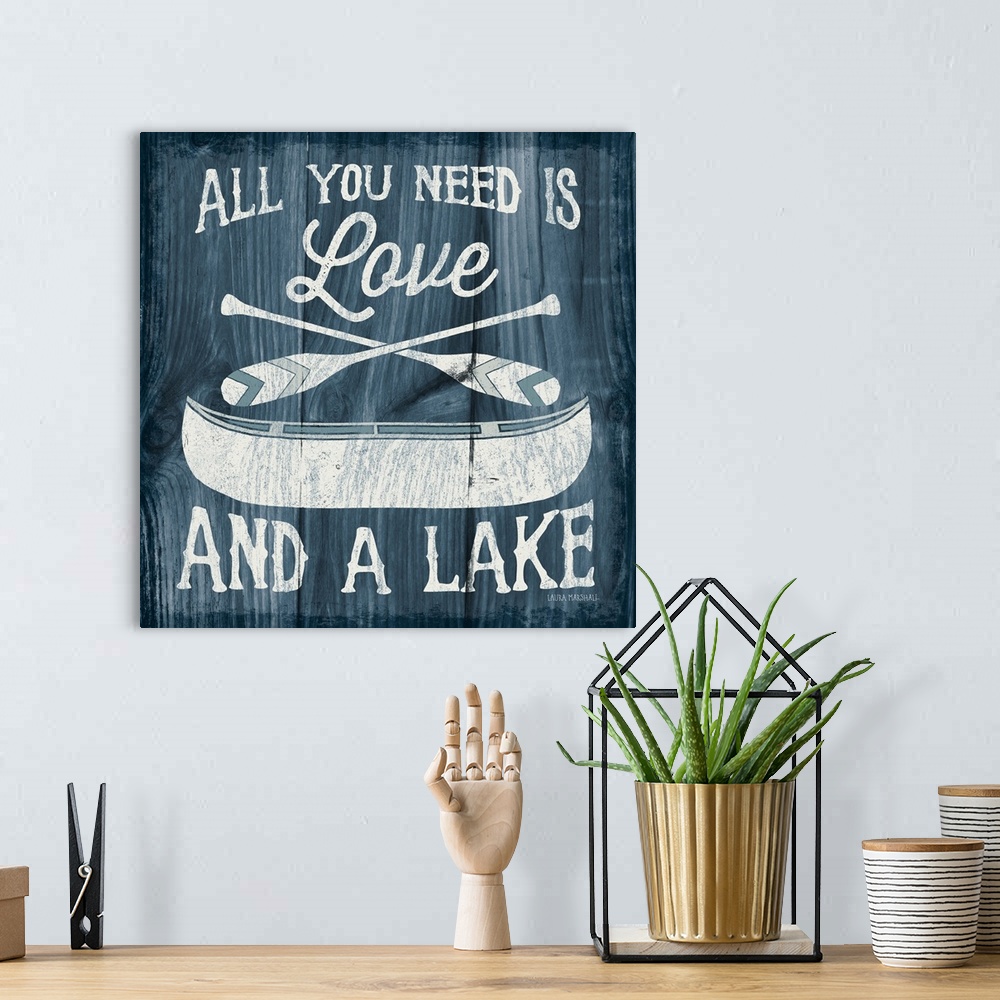 A bohemian room featuring "All You Need is Love And a Lake" in white with an illustration of a canoe and paddles on a dark ...