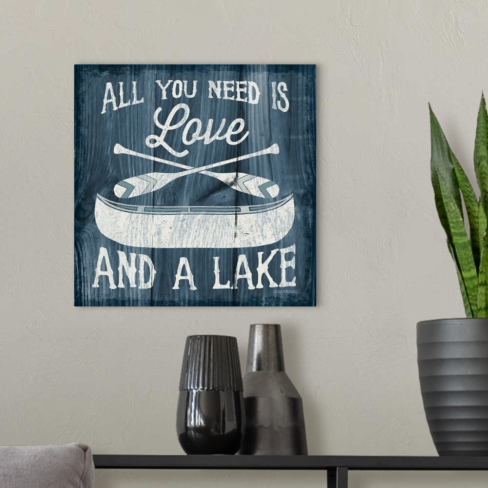 A modern room featuring "All You Need is Love And a Lake" in white with an illustration of a canoe and paddles on a dark ...