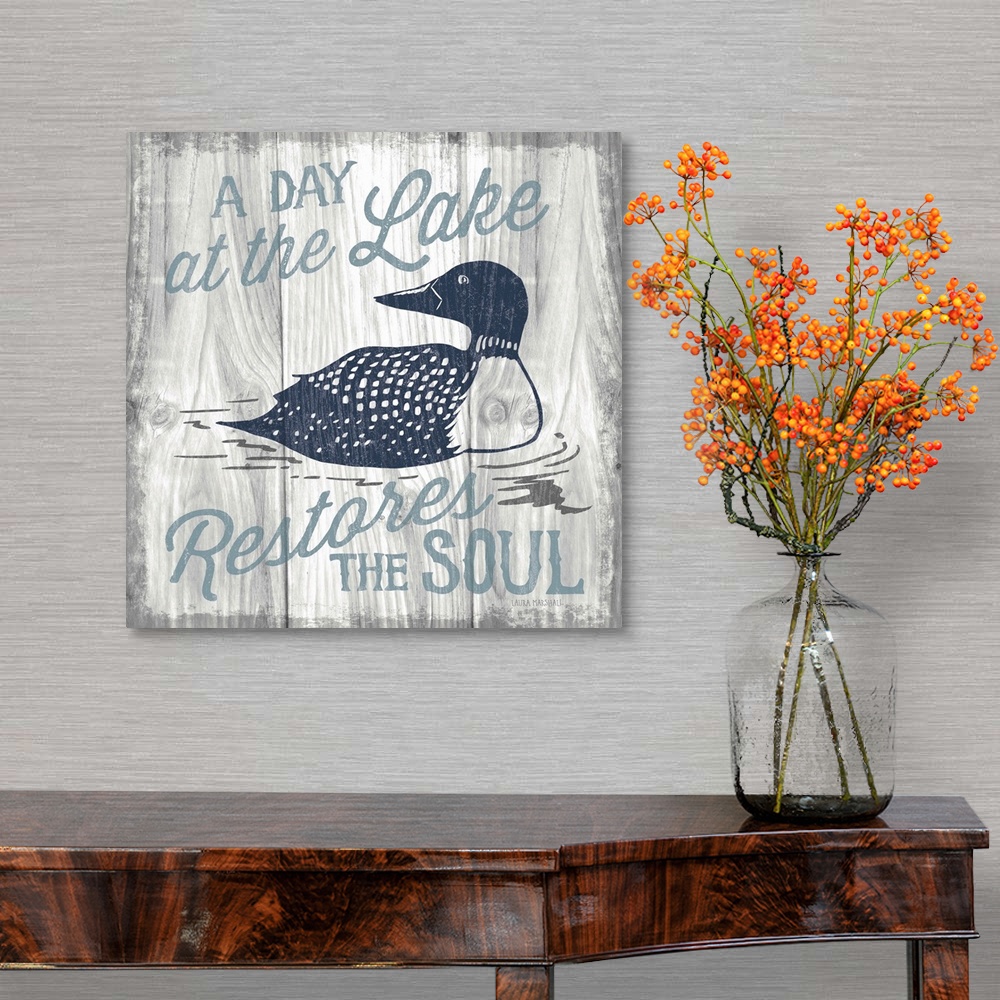 A traditional room featuring "A Day at the Lake Restores the Soul" in blue with an illustration of a duck on a grey wood grain...