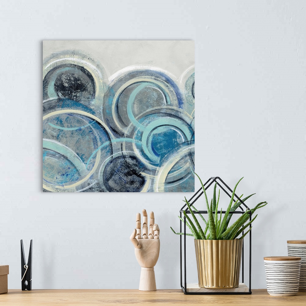 A bohemian room featuring Abstract painting with circular shapes layered on top of each other in shades of blue with some y...