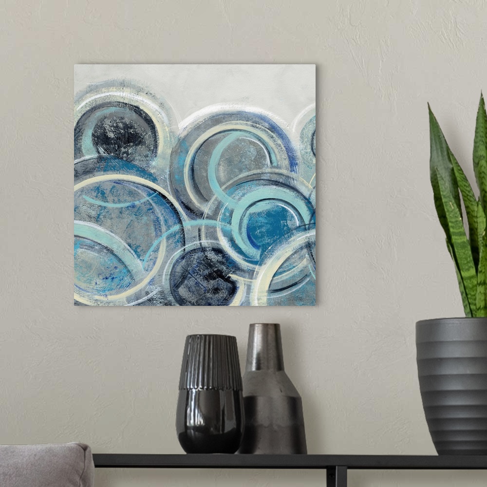 A modern room featuring Abstract painting with circular shapes layered on top of each other in shades of blue with some y...