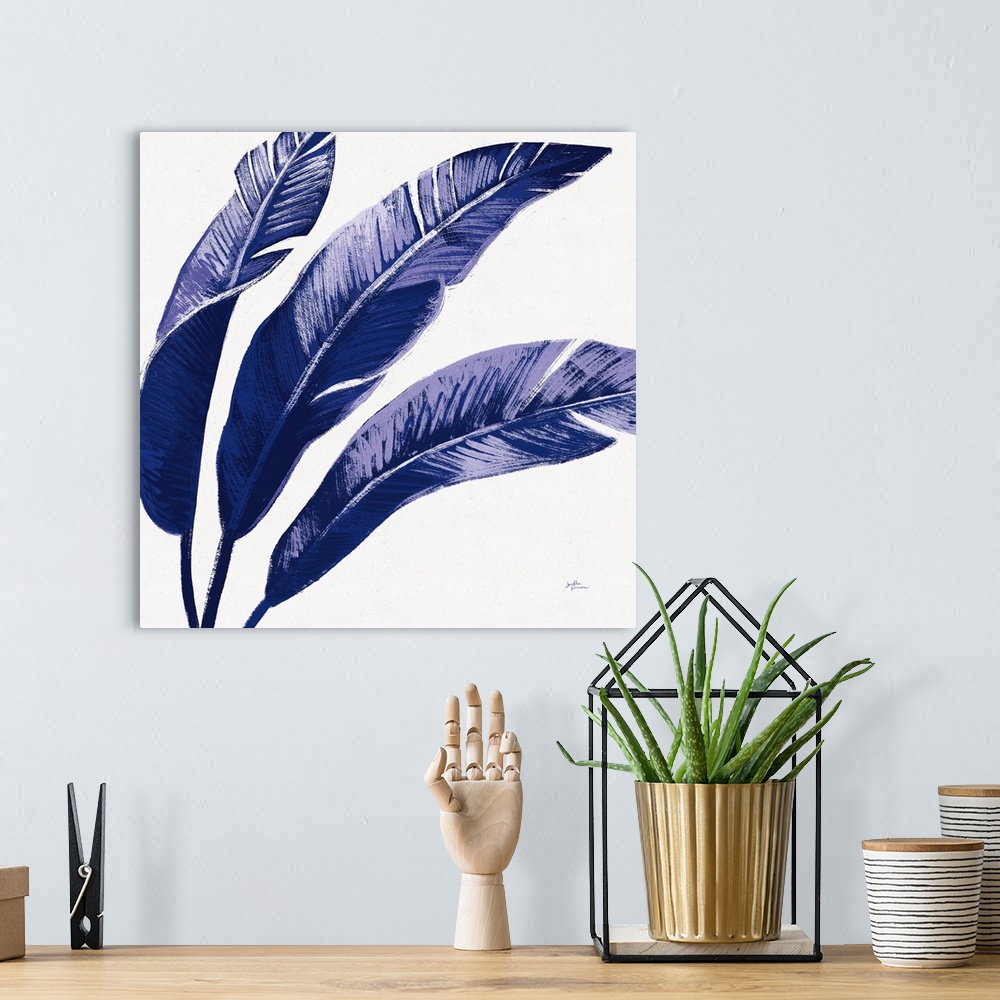 A bohemian room featuring Square decorative artwork of large palm leaves in shades of blue.