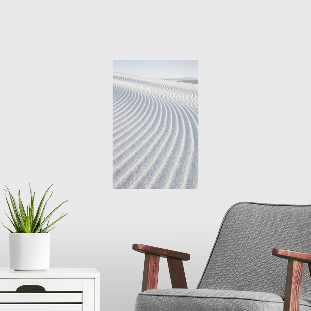A modern room featuring A vertical photograph of ripples in the sand dunes created by the wind.