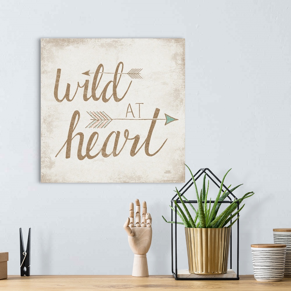 A bohemian room featuring "Wild At Heart" with two arrows on a beige brushed backdrop.