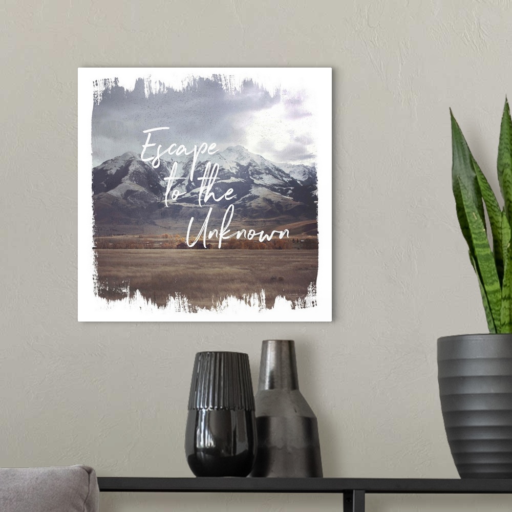 A modern room featuring "Escape to the Unknown" written on top of a photograph of snow capped mountains with brushstroke ...