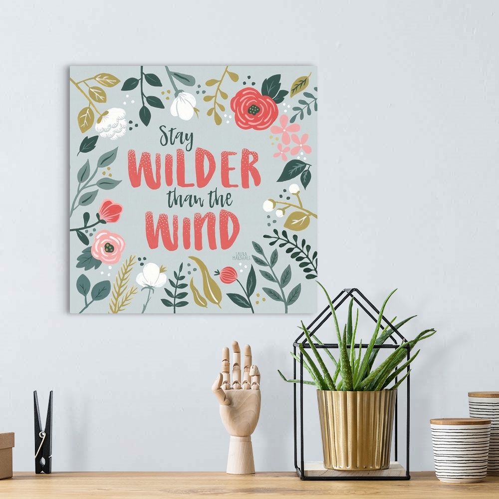 A bohemian room featuring "Stay Wilder Than The Wind" framed by wild flowers on a gray background.