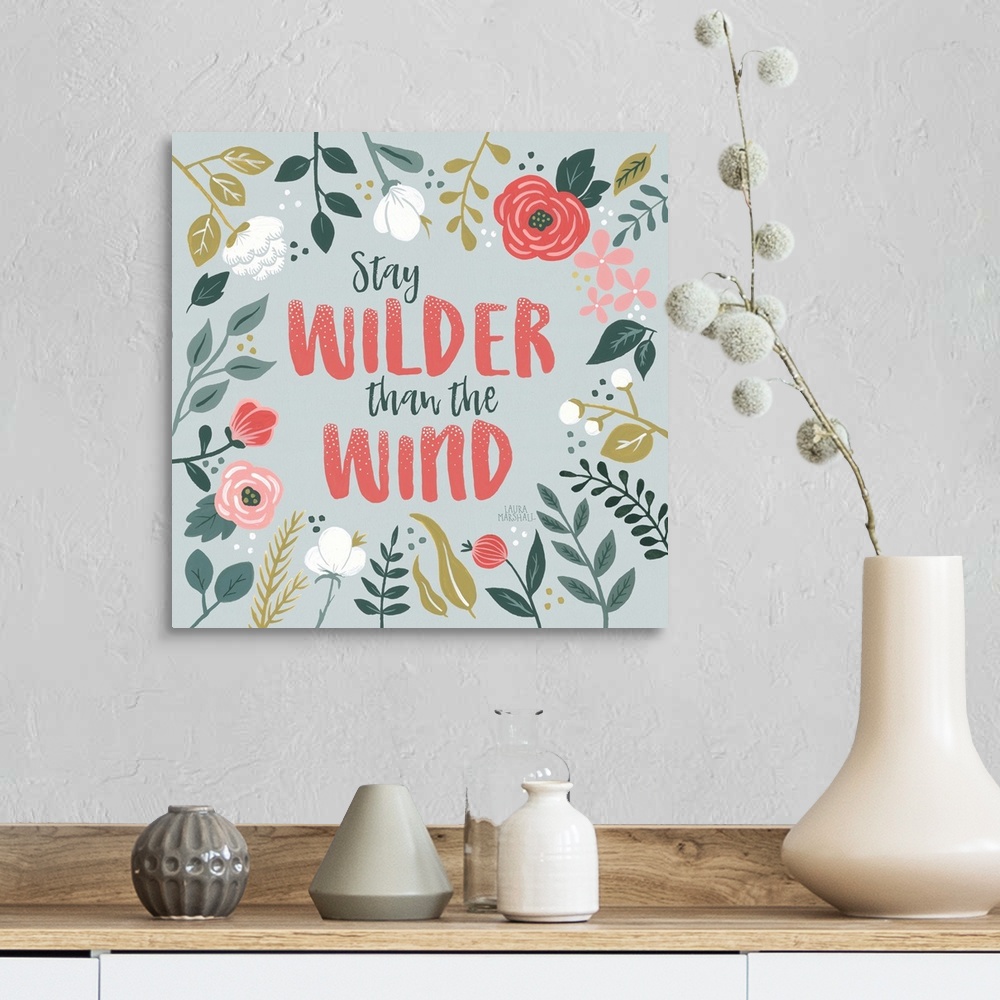 A farmhouse room featuring "Stay Wilder Than The Wind" framed by wild flowers on a gray background.